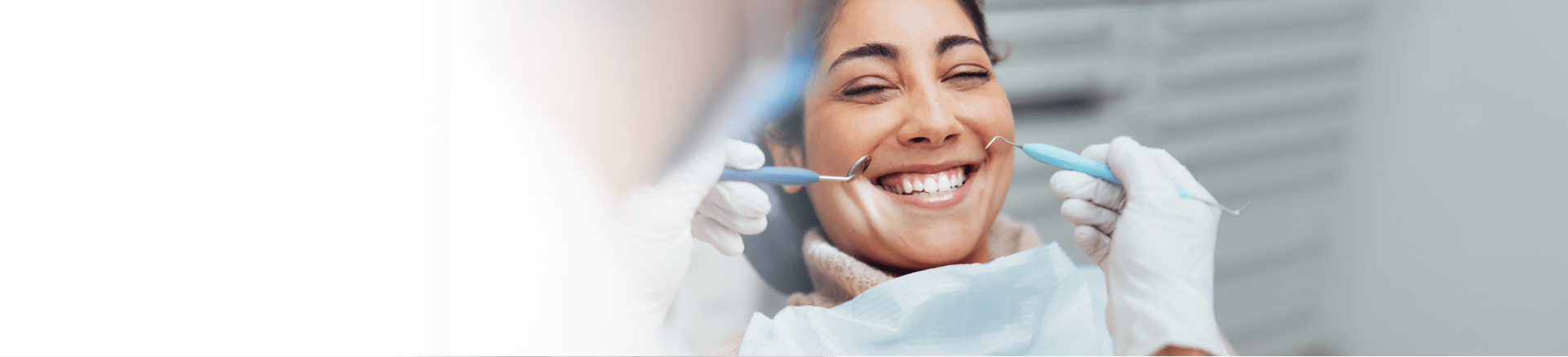 woman smiling as she gets her mouth checked by dentist
