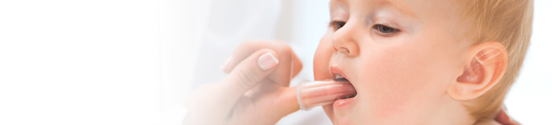 adult using finger brush on baby